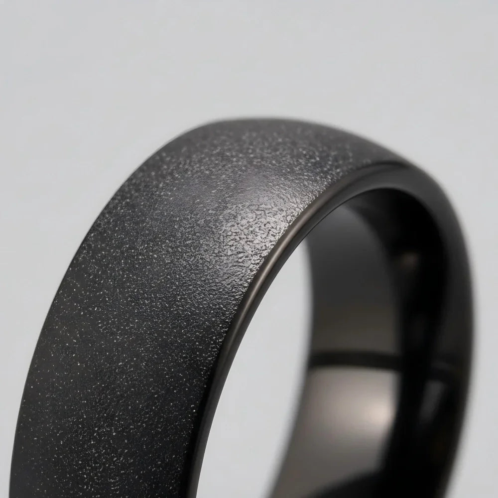 Macro detail of raw granular texture and seamless matte surface on The Shadow Monolith showcasing sandblasted Black Aerospace-grade Tungsten.