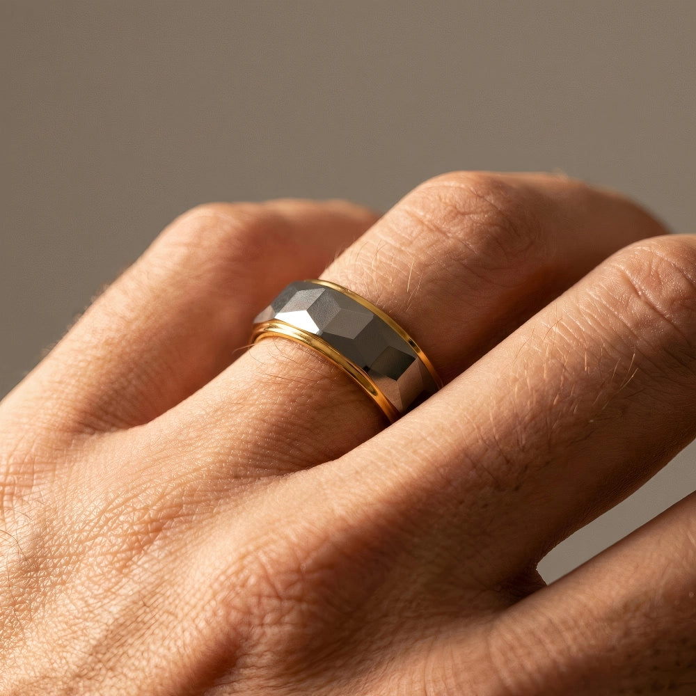 Man's hand wearing The Prismatic Pillar Aerospace-grade Tungsten ring resting under warm focused studio lighting.