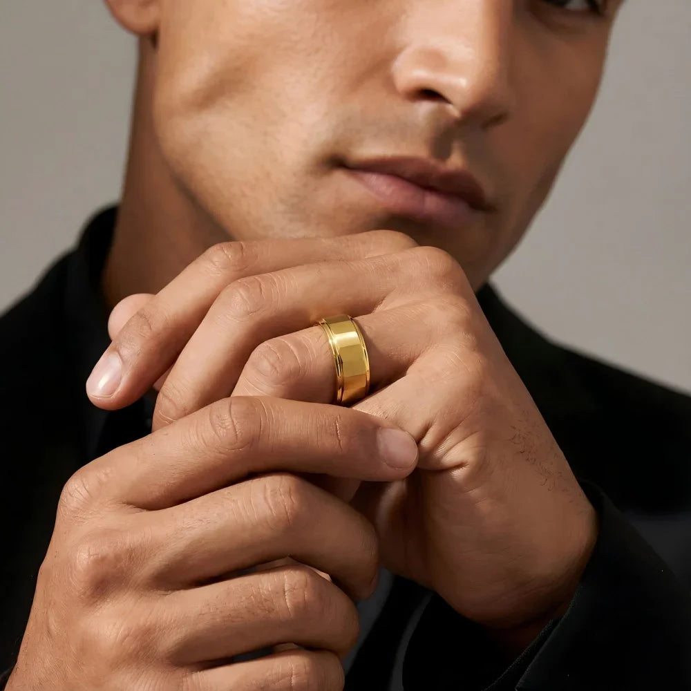 Man's hands clasped together wearing The Titan 18K Gold PVD Aerospace-grade Tungsten ring in a focused, minimalist studio setting.
