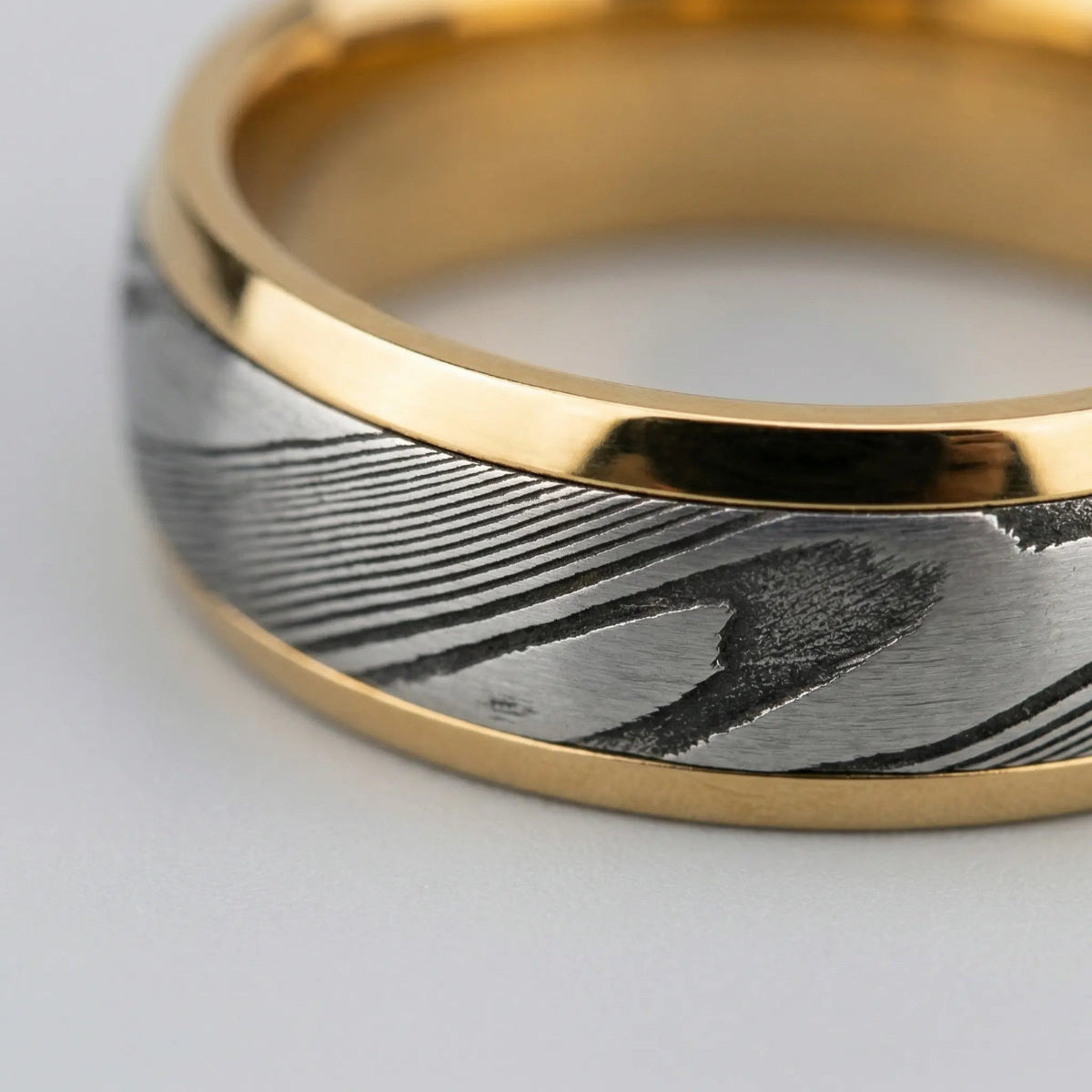 Macro detail of stratigraphic acid-etching on Damascus steel showcasing unique forged grain.