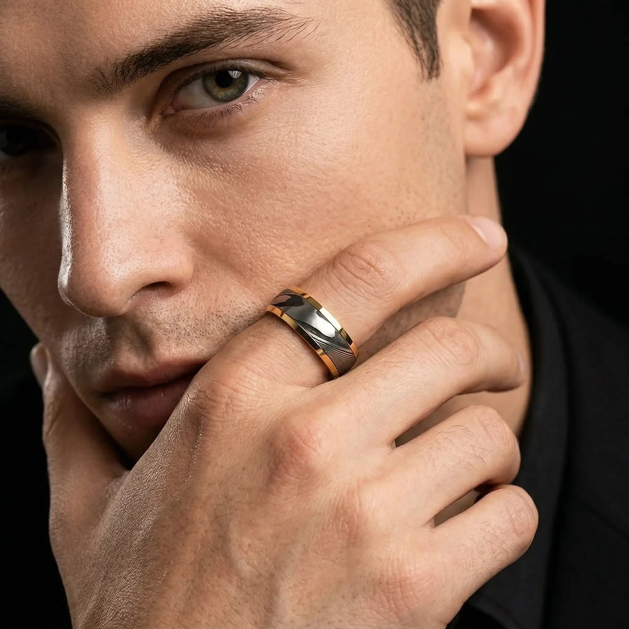 Close-up of Man's hand wearing The Axis Damascus ring with gold and dark accents,serving as a physical anchor for focus.