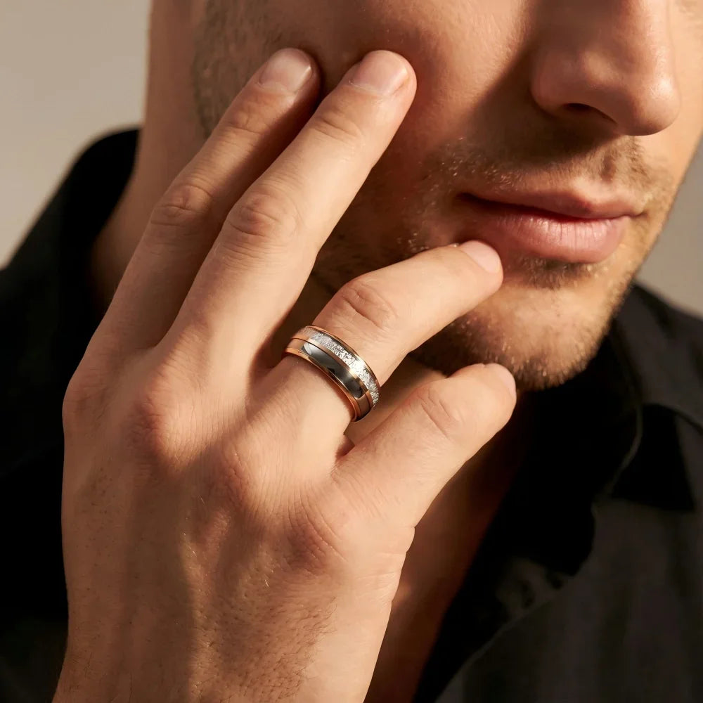 Man's hand wearing The Ethereal Core 18K Rose Gold PVD Aerospace-grade Tungsten ring with fingers lightly brushing the cheek in a focused, contemplative gesture.