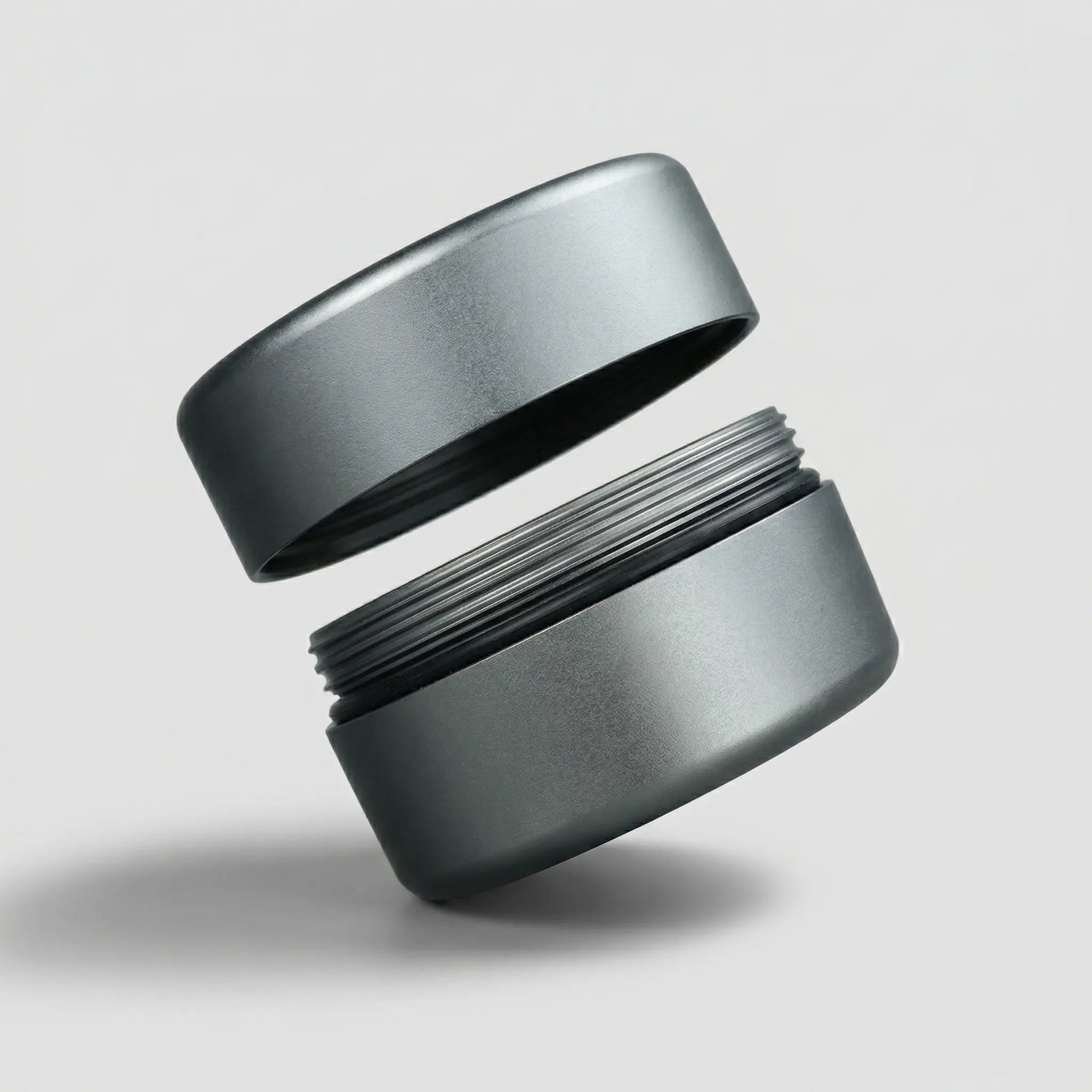 Matte metallic cylindrical jewelry container with threaded lid, floating on grey background