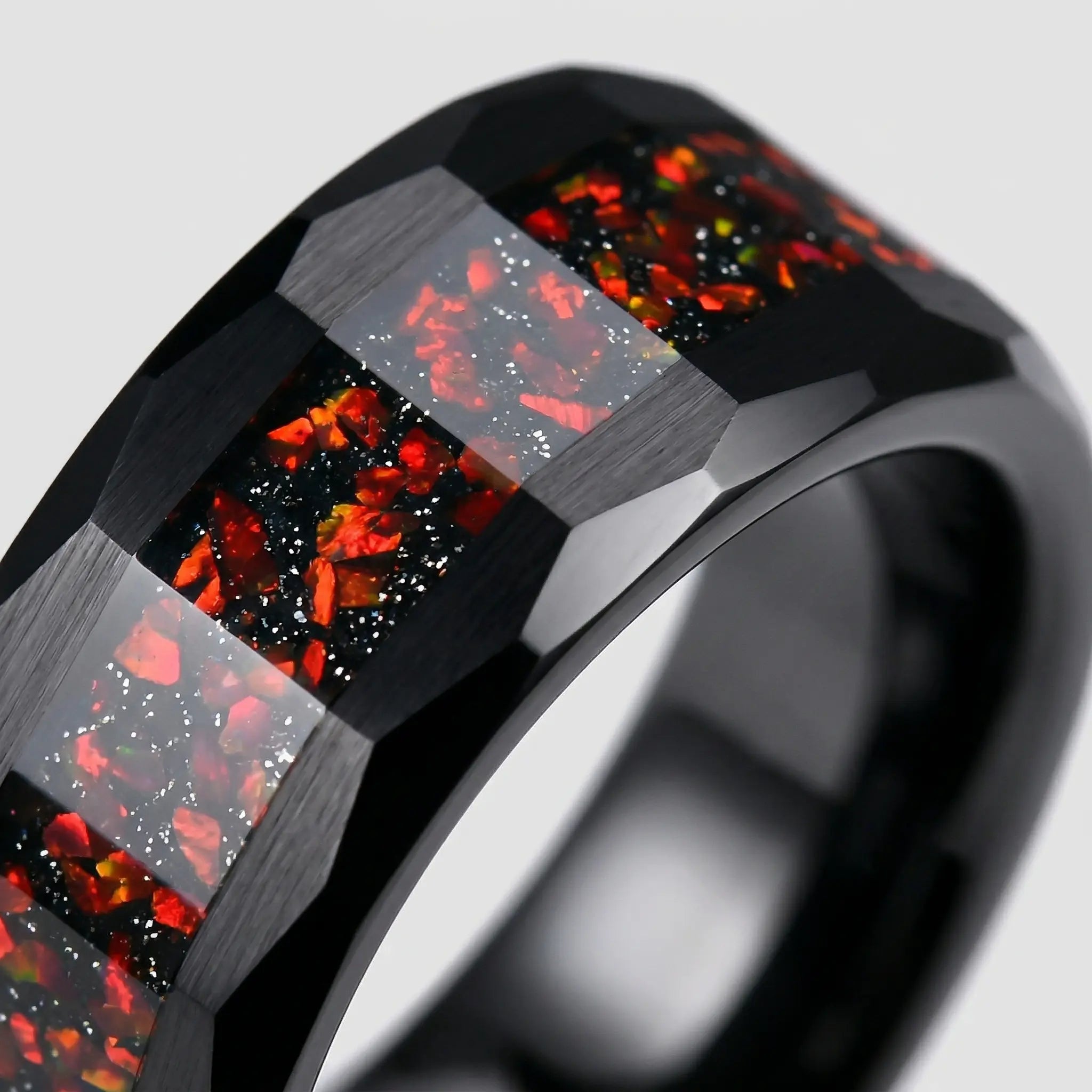 Macro detail of faceted geometric edges on The Ignis Forge showcasing Black Aerospace-grade Tungsten and crushed Red Opal.