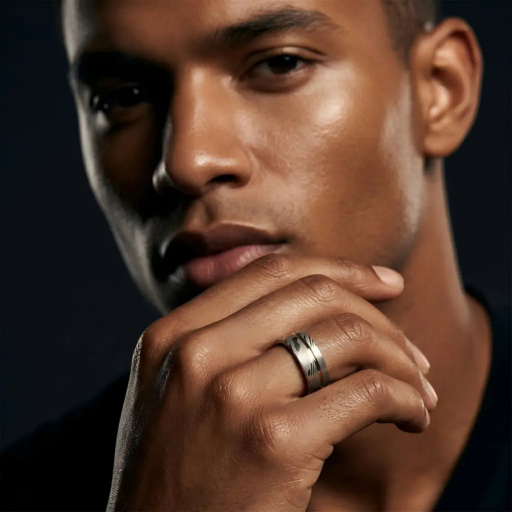 Man wearing a Meridian Fold showcasing Forged Damascus Steel and 18K Gold PVD coating. on his hand, close-up view