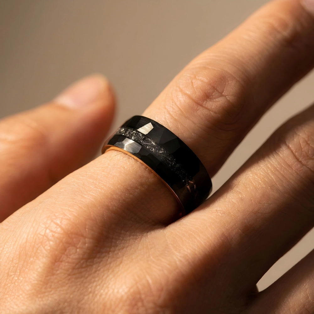 Man's hand wearing The Celestial Rift 18K Rose Gold PVD and Aerospace-grade Tungsten ring resting naturally under warm focused studio lighting.
