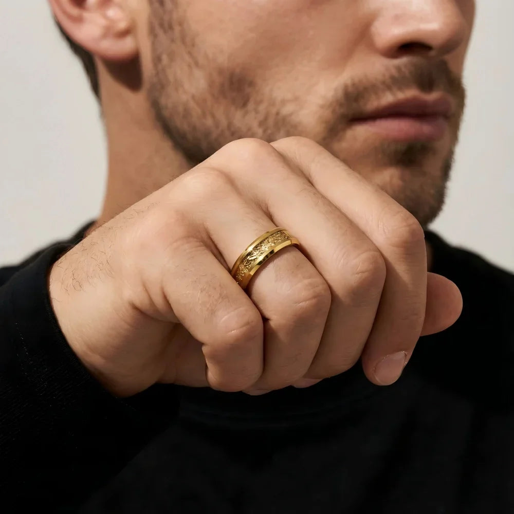 Man's hand wearing The Gilded Grain 18K Gold PVD ring with fingers resting thoughtfully near the chin in a focused pose.