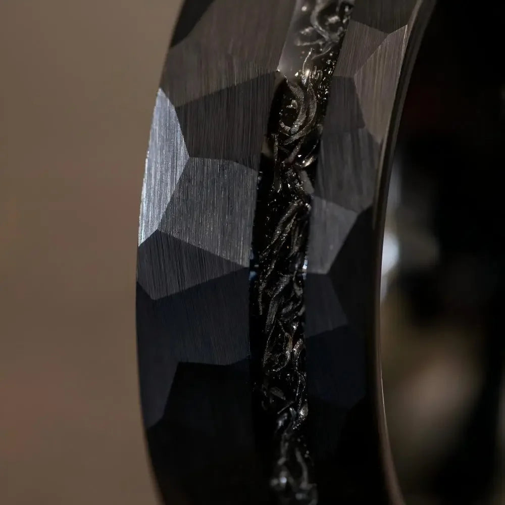 Macro detail of faceted geometric edges and organic crystalline texture on The Midnight Rift showcasing hammered Black Aerospace-grade Tungsten.