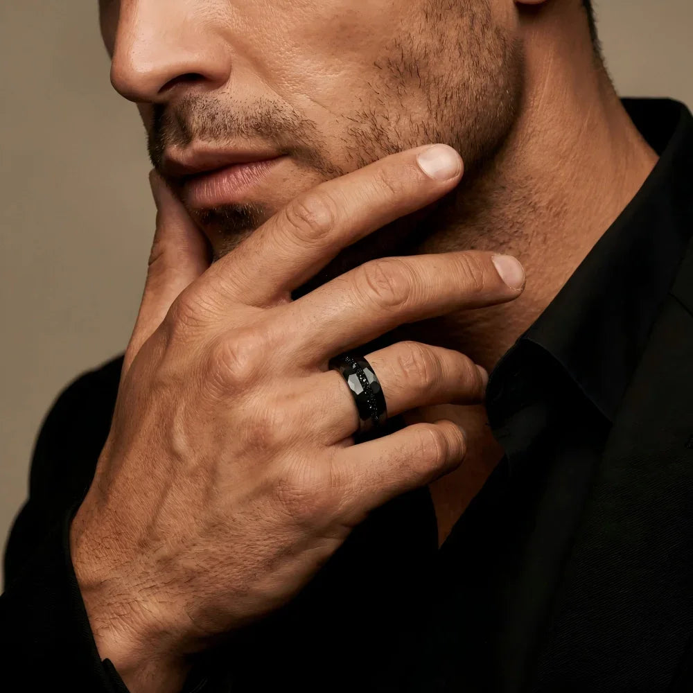 Man's hand wearing The Midnight Rift Black Aerospace-grade Tungsten ring, with fingers resting thoughtfully against the jawline in a focused studio setting.