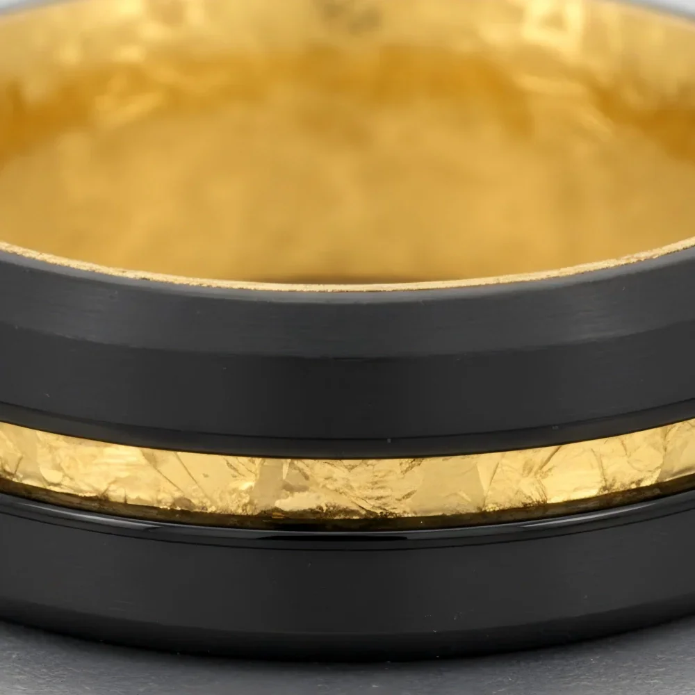 Macro detail of brushed finish and textured gold leaf groove on The Aurelius Spark showcasing Black Aerospace-grade Tungsten and 18K Gold PVD coating.